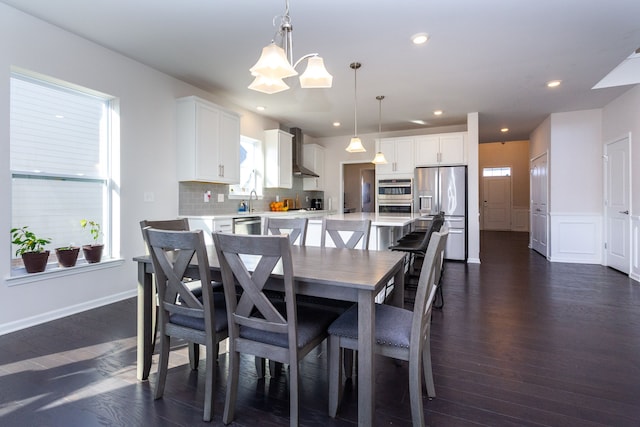 dining space with a decorative wall, a notable chandelier, recessed lighting, and dark wood-style flooring