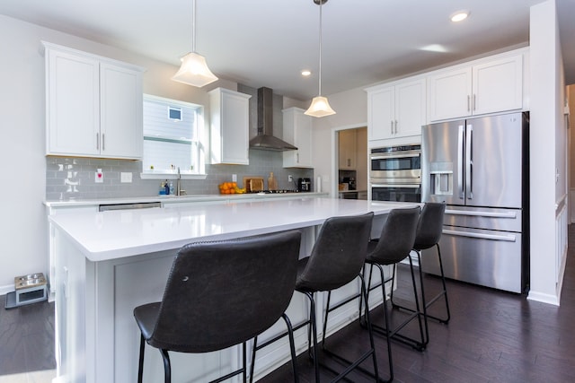 kitchen with dark wood-style floors, tasteful backsplash, appliances with stainless steel finishes, and wall chimney exhaust hood