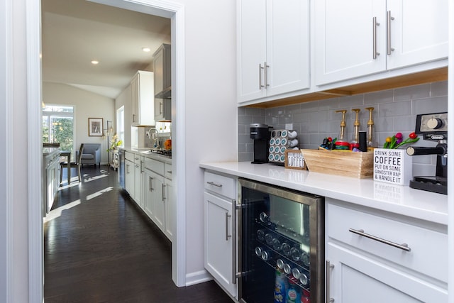 interior space featuring beverage cooler, dark wood finished floors, lofted ceiling, light countertops, and tasteful backsplash