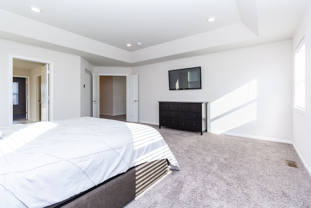 carpeted bedroom with a raised ceiling, visible vents, and baseboards