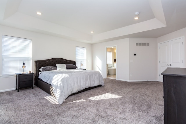 bedroom featuring a tray ceiling, carpet floors, and visible vents