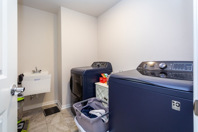 laundry room with laundry area, washing machine and dryer, baseboards, and a sink