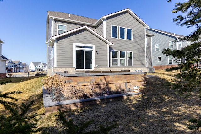 rear view of house featuring brick siding and a lawn