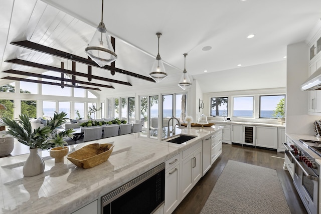 kitchen with a sink, dark wood-style floors, white cabinetry, stainless steel appliances, and hanging light fixtures