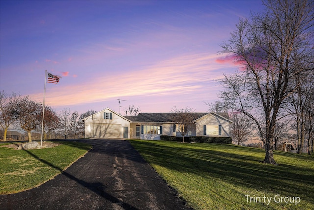 view of front of property with aphalt driveway, a yard, and a garage