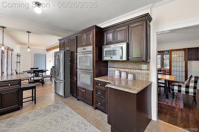 19344 Strathcona Dr, Detroit, MI 48203 - kitchen with stainless steel appliances, dark brown cabinetry, ornamental molding, decorative backsplash, and light stone countertops