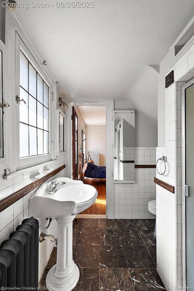 19344 Strathcona Dr, Detroit, MI 48203 - bathroom featuring radiator heating unit, tile walls, marble look tiles, and lofted ceiling