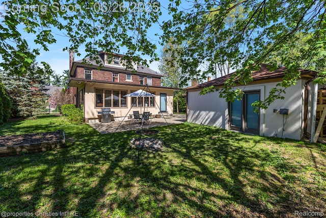 19344 Strathcona Dr, Detroit, MI 48203 - rear view of house featuring a patio area, a lawn, stucco siding, a chimney, and an outbuilding