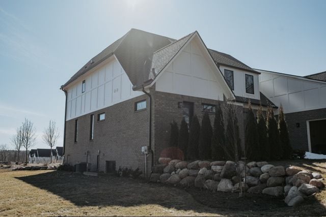 72460 Henry D Dr, Romeo, MI 48065 - view of property exterior featuring brick siding, a lawn, board and batten siding, and central AC