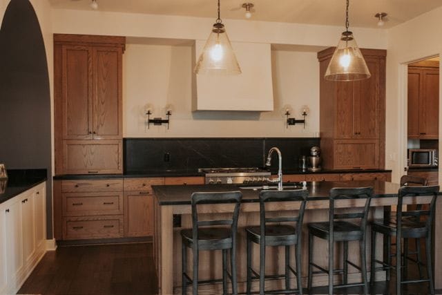 72460 Henry D Dr, Romeo, MI 48065 - kitchen featuring hanging light fixtures, dark countertops, stainless steel microwave, and dark wood-type flooring