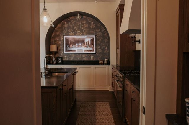 72460 Henry D Dr, Romeo, MI 48065 - kitchen with stainless steel range, a sink, dark countertops, wall chimney exhaust hood, and hanging light fixtures
