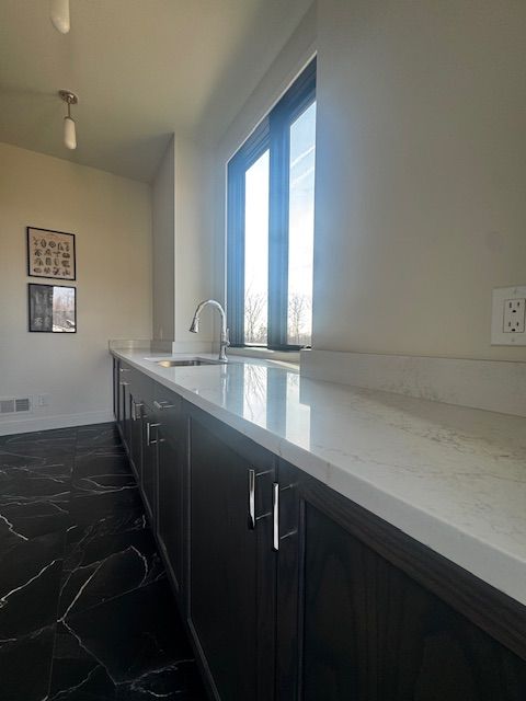 72460 Henry D Dr, Romeo, MI 48065 - kitchen with dark cabinetry, light stone countertops, visible vents, a sink, and marble finish floor
