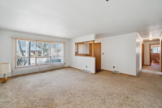 unfurnished living room with a wealth of natural light, visible vents, and carpet