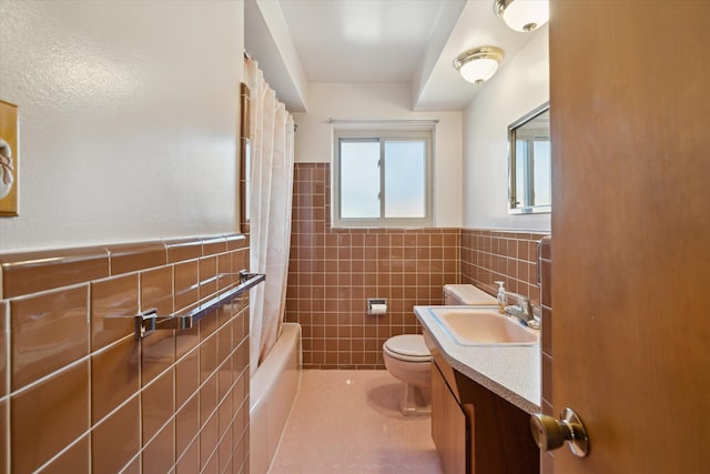 full bathroom with a wainscoted wall, toilet, vanity, tile patterned floors, and tile walls