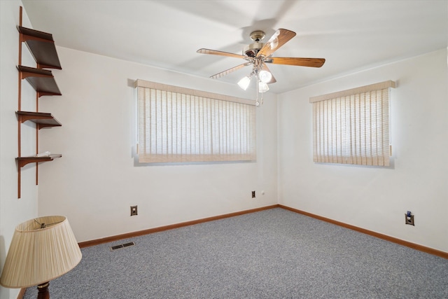 empty room with baseboards, visible vents, carpet floors, and ceiling fan