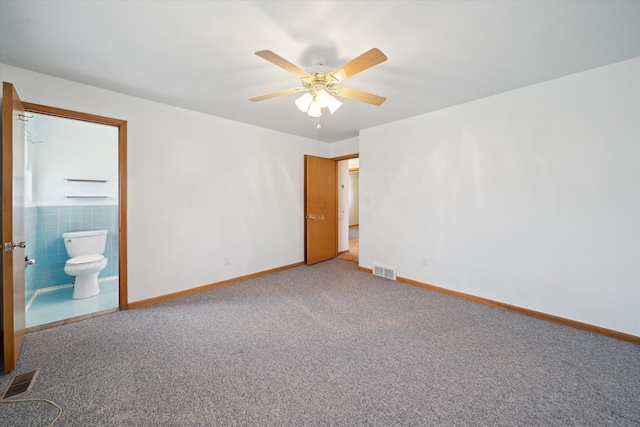 unfurnished bedroom with tile walls, visible vents, carpet floors, and connected bathroom