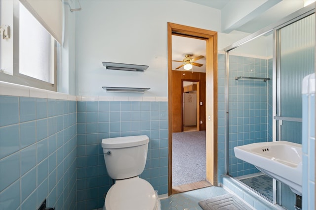 bathroom with a stall shower, ceiling fan, tile walls, toilet, and tile patterned floors