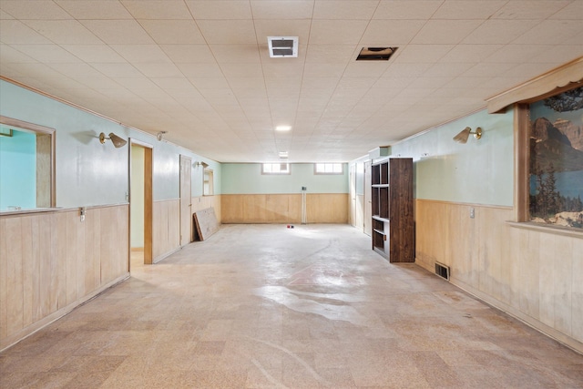 basement with visible vents, wood walls, and wainscoting