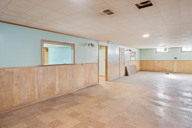 below grade area featuring wooden walls, a wainscoted wall, tile patterned floors, and visible vents