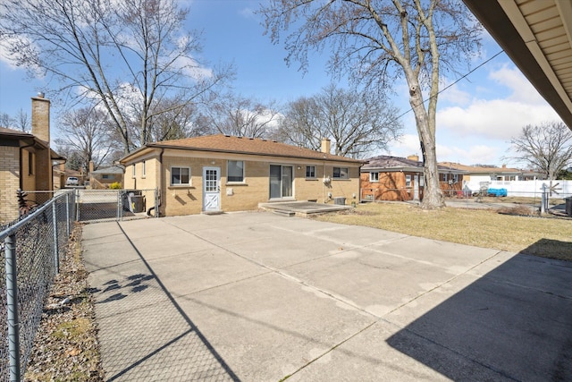 rear view of house with brick siding, fence, a chimney, a yard, and a patio area