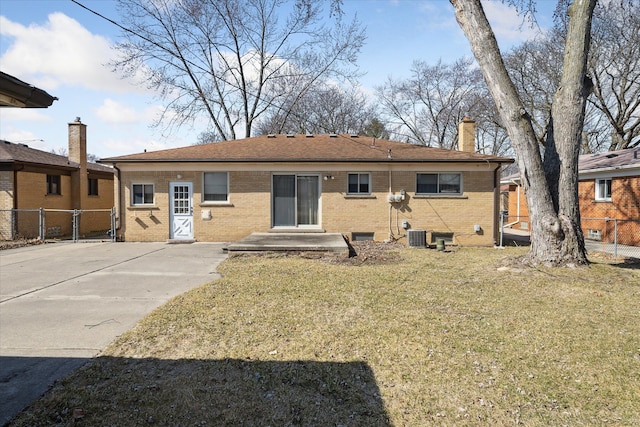 back of house featuring fence, a yard, a chimney, concrete driveway, and brick siding