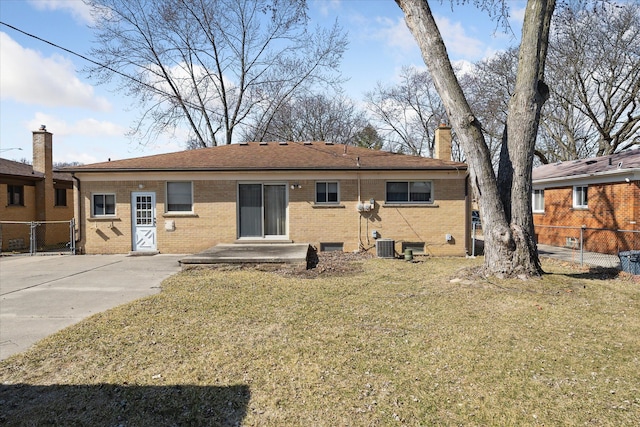 back of house featuring brick siding, a chimney, a yard, and fence