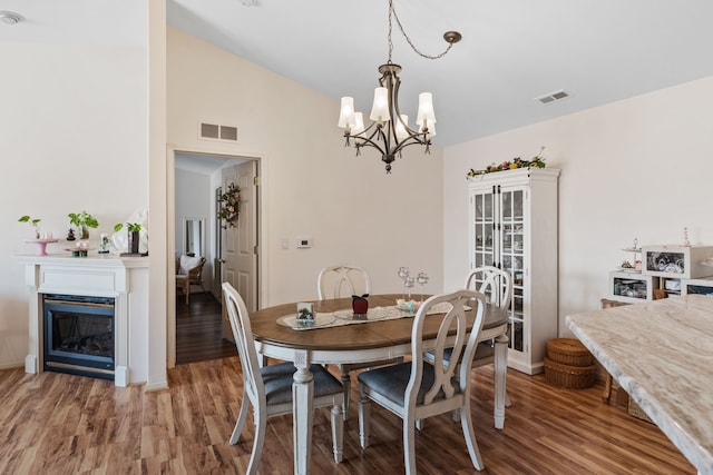 dining area featuring visible vents, a notable chandelier, and wood finished floors