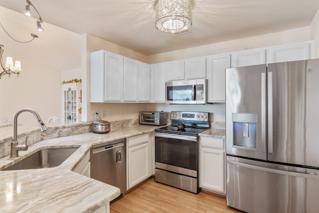 kitchen featuring a chandelier, stainless steel appliances, light stone counters, and a sink