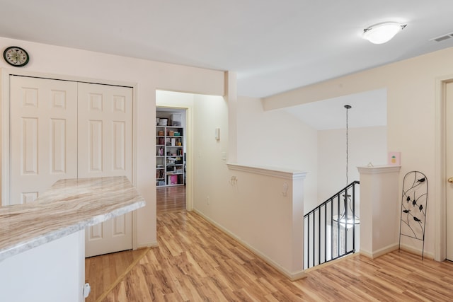 hall featuring visible vents, baseboards, vaulted ceiling, an upstairs landing, and light wood-style floors