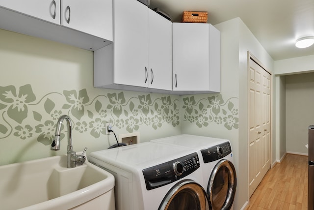 laundry room with washer and dryer, cabinet space, light wood-style floors, and a sink