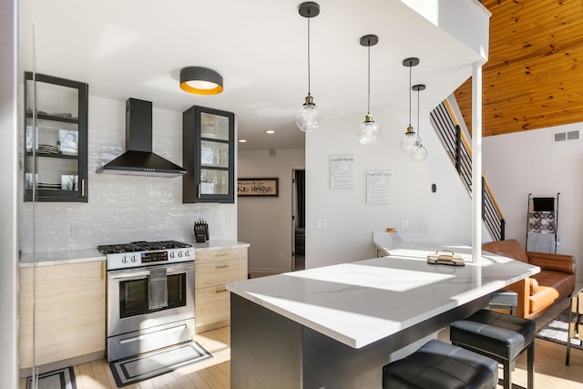 2060 S Algonquin Dr, Benton Harbor, MI 49022 - kitchen with wall chimney range hood, stainless steel gas range, light wood-style floors, a breakfast bar area, and modern cabinets