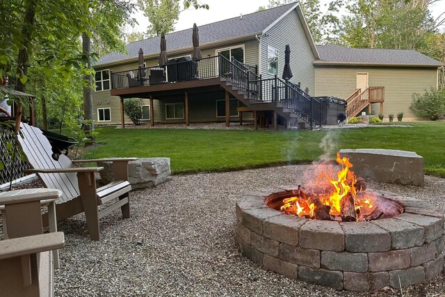 back of house with stairway, a yard, a fire pit, and a wooden deck