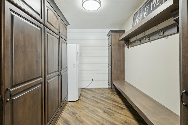 mudroom with wood walls and light wood-style floors