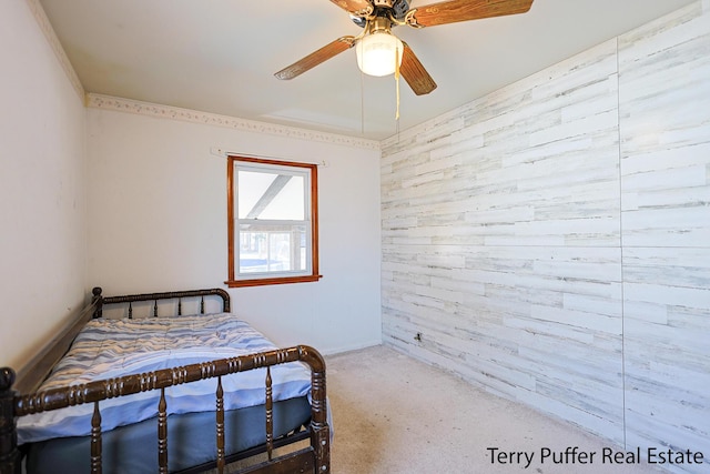 carpeted bedroom featuring wood walls and a ceiling fan