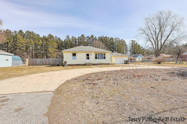 view of front of home featuring entry steps, concrete driveway, fence, and an outdoor structure