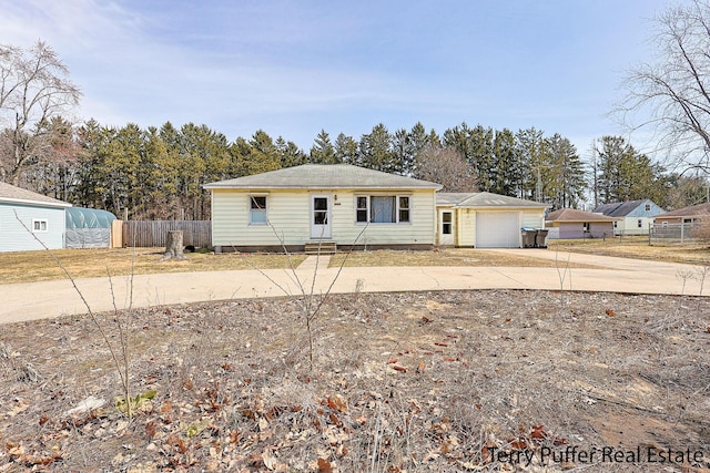 view of front facade with entry steps, concrete driveway, an attached garage, and fence