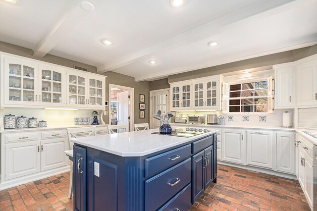 kitchen with beamed ceiling, electric stovetop, brick floor, white cabinets, and blue cabinets