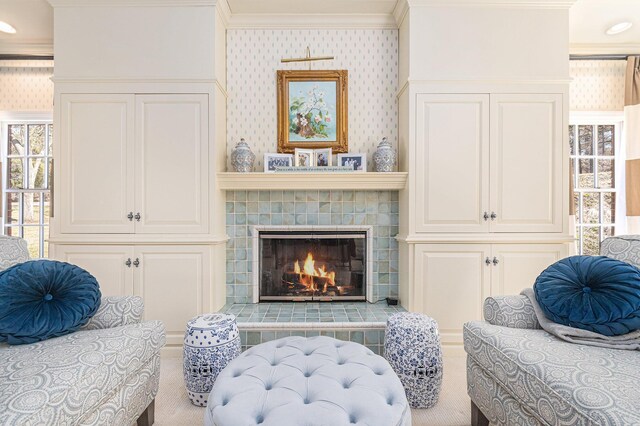 living area with a tiled fireplace and ornamental molding