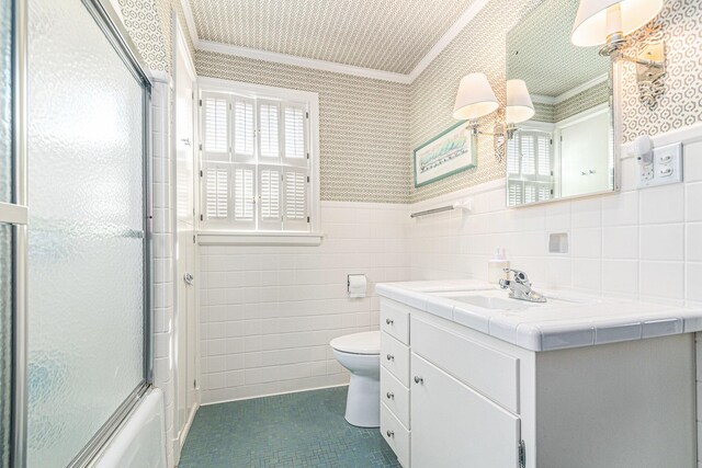 full bathroom with vanity, ornamental molding, wainscoting, toilet, and tile walls