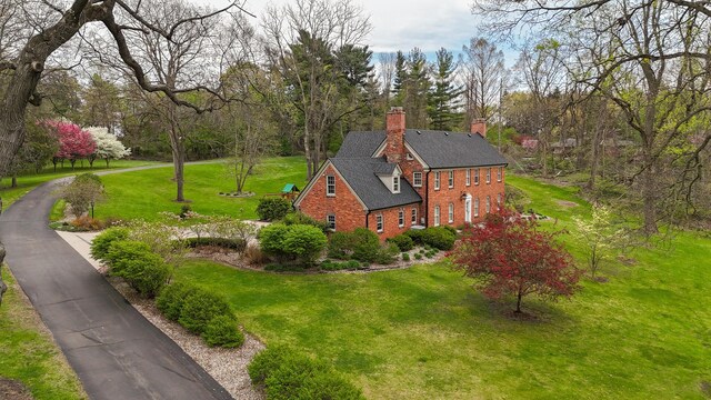 exterior space featuring brick siding, a lawn, and a chimney