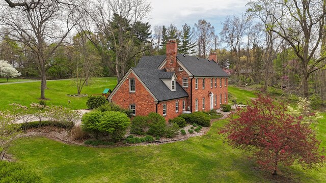 view of home's exterior with a lawn, a chimney, roof with shingles, and brick siding