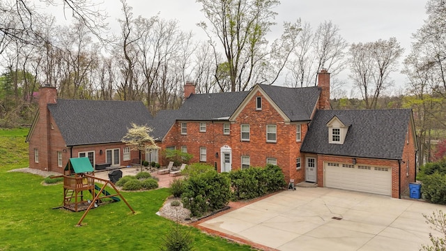 view of front facade with brick siding, a front lawn, driveway, and a chimney