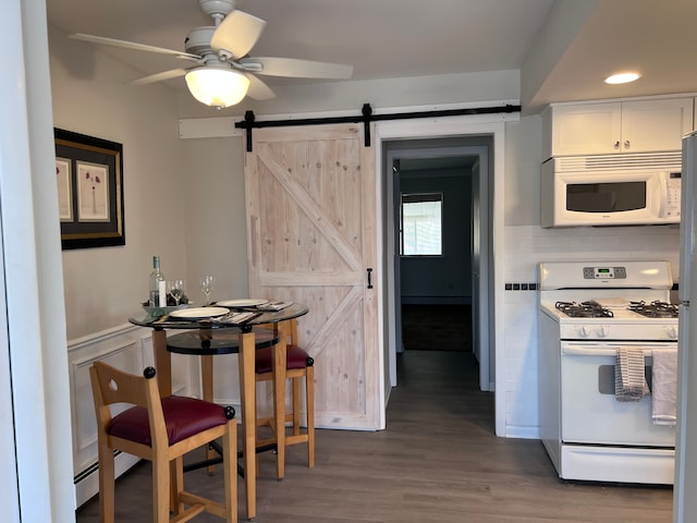 kitchen with wood finished floors, a barn door, white appliances, white cabinets, and ceiling fan