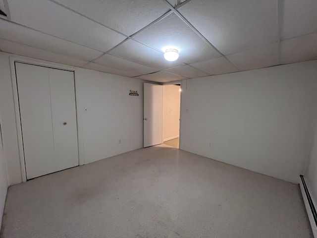 unfurnished bedroom featuring baseboard heating and a drop ceiling