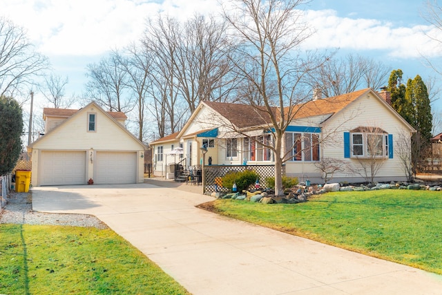 view of front facade with a front yard, a chimney, a garage, an outbuilding, and driveway