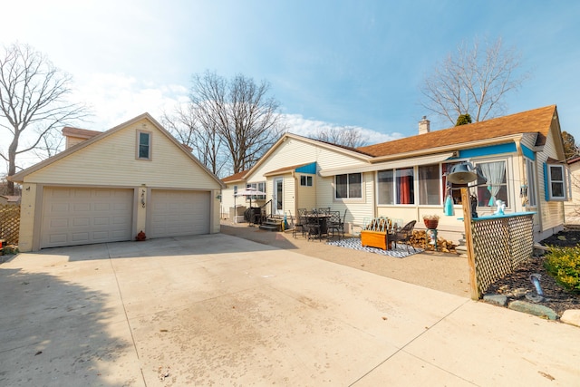 view of front of property with an outdoor structure, concrete driveway, a garage, and a chimney