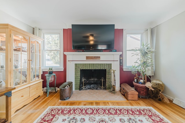 living room with a brick fireplace, wood finished floors, and baseboards