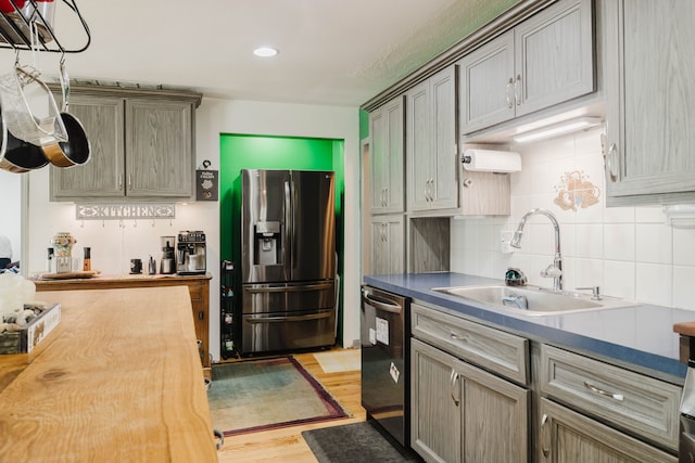 kitchen with light wood-type flooring, tasteful backsplash, appliances with stainless steel finishes, and a sink