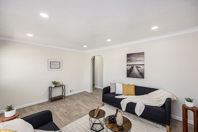 living area featuring arched walkways, visible vents, baseboards, and wood finished floors