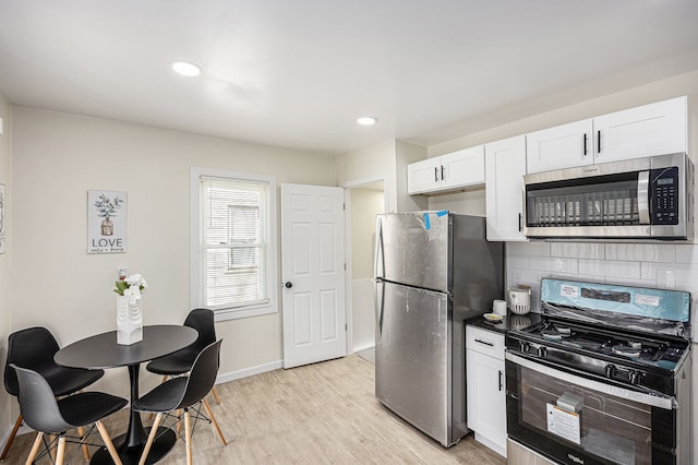 kitchen featuring baseboards, light wood-style flooring, stainless steel appliances, decorative backsplash, and white cabinetry